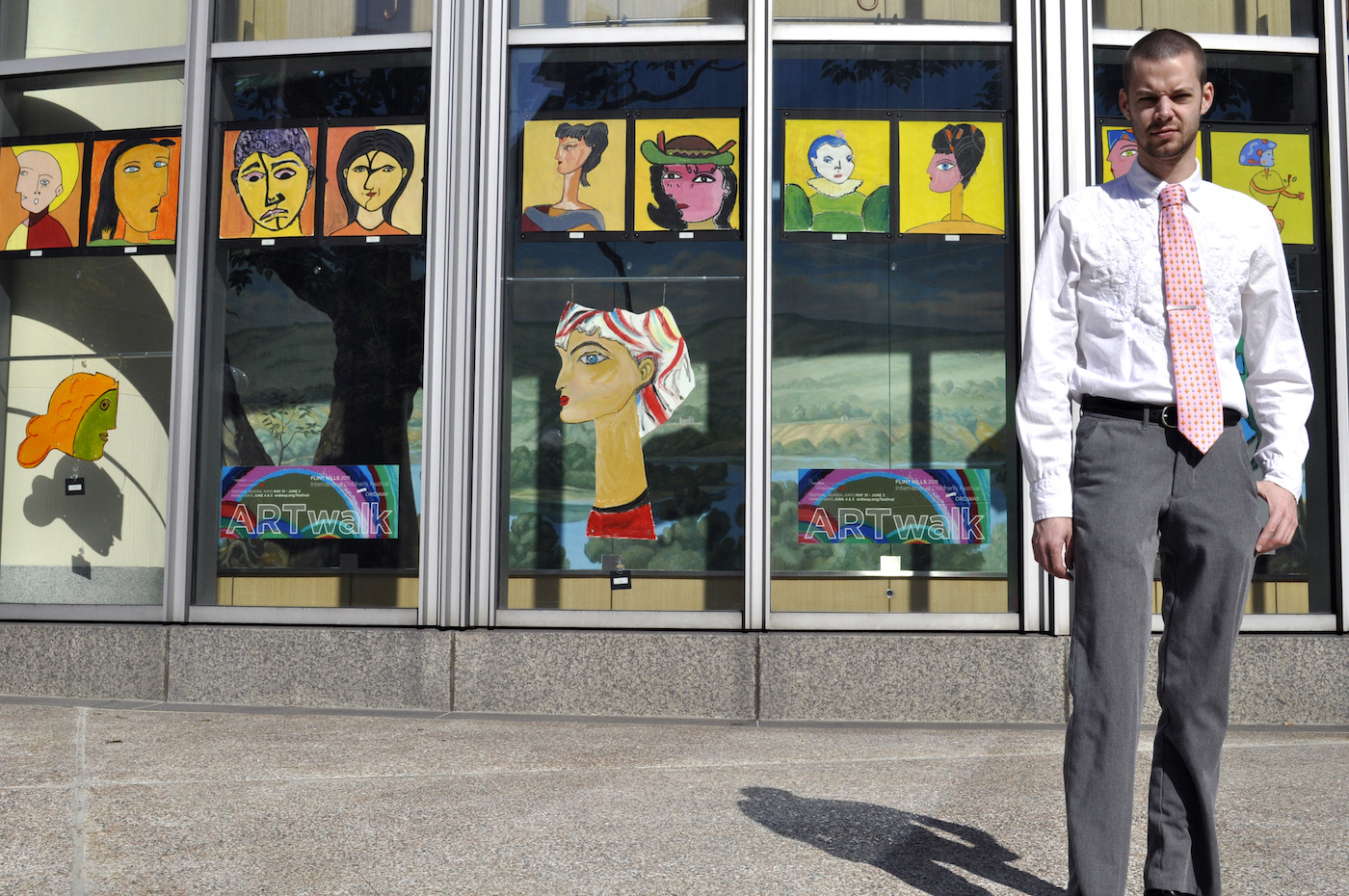 Man standing in front of window display of colorful portraits